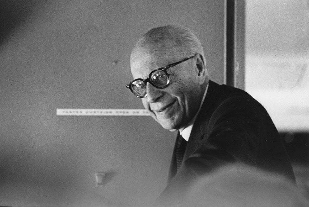 George Szell as an old man. Hunched over while sitting on an airplane, but smiling for the camera.