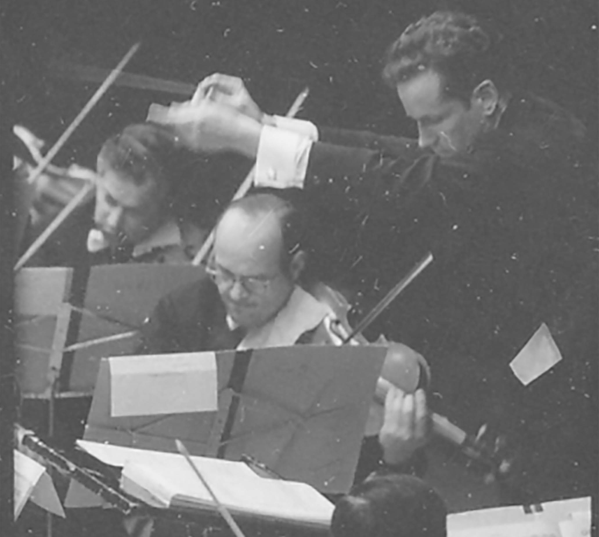 A youthful Louis Lane conducts the Orchestra. Everyone wears a serious, intense expression.