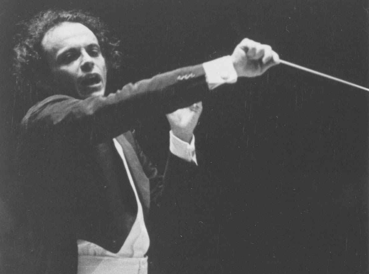 Maazel is conducting the Orchestra. His hair looks wild, and he is conducting aggressively.